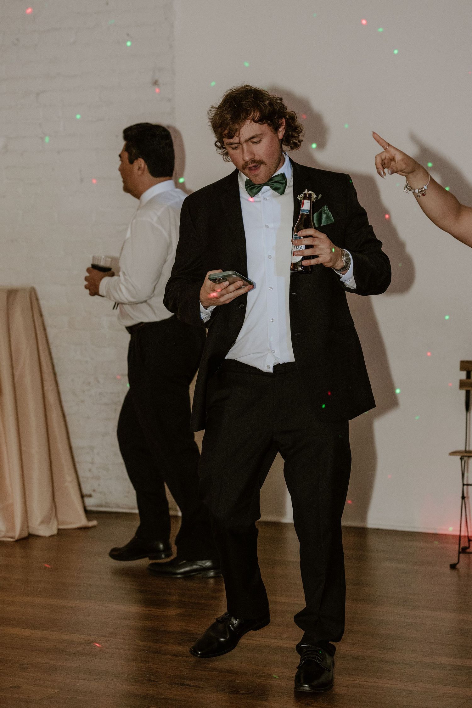 Wedding guests dancing on hardwood floor with colorful disco lights.