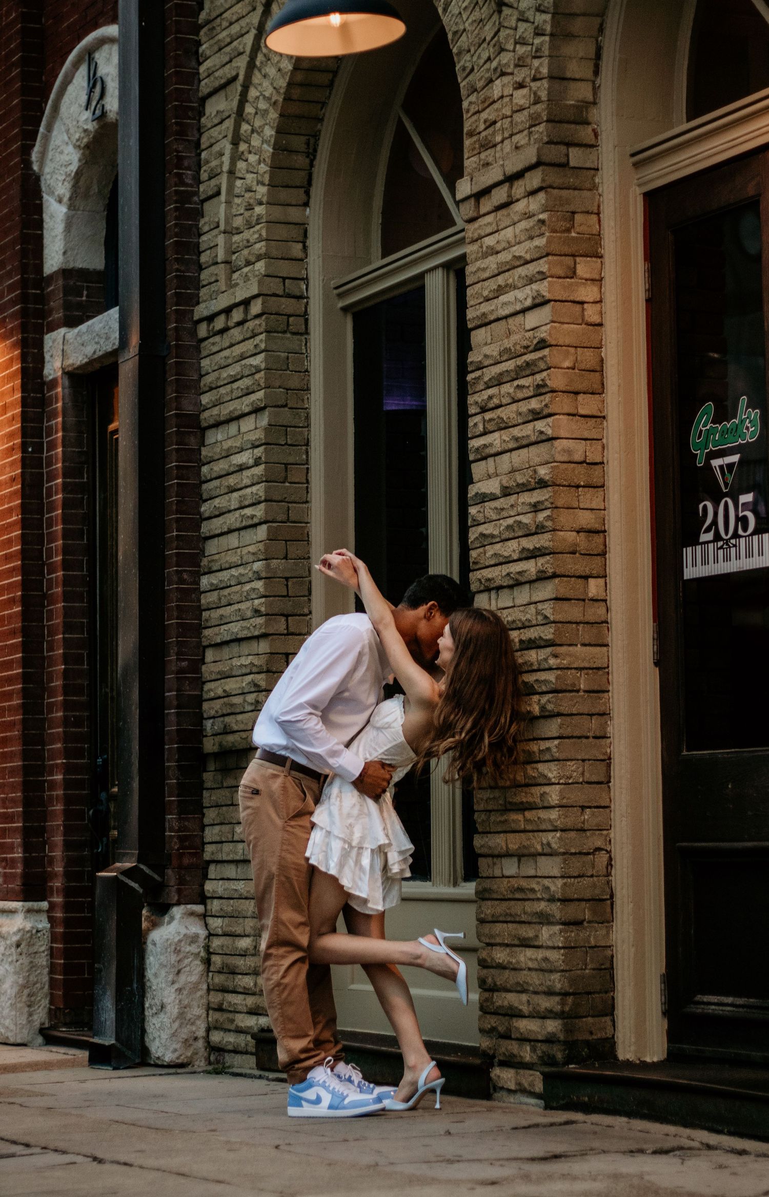 Stylish couple posing against brick wall in urban setting.