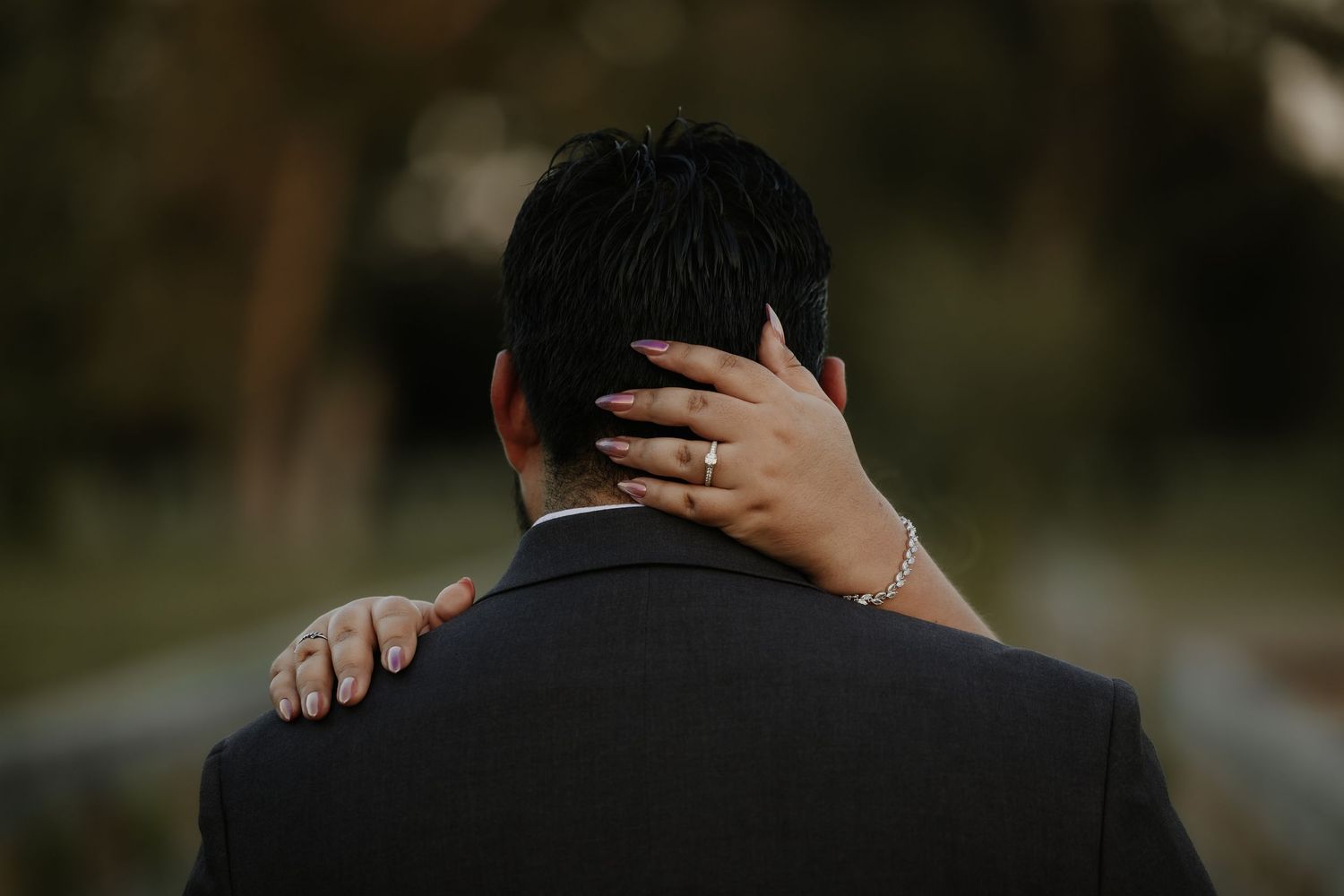 Close-up view of formal suit and hands on shoulders during intimate moment.