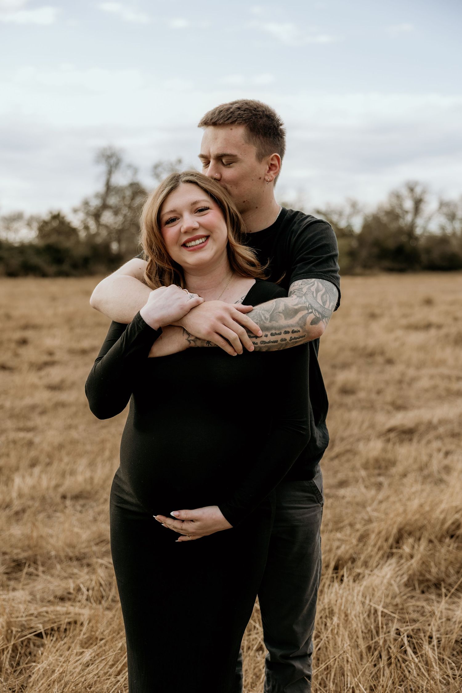 Happy expecting couple sharing tender moment in autumn field.