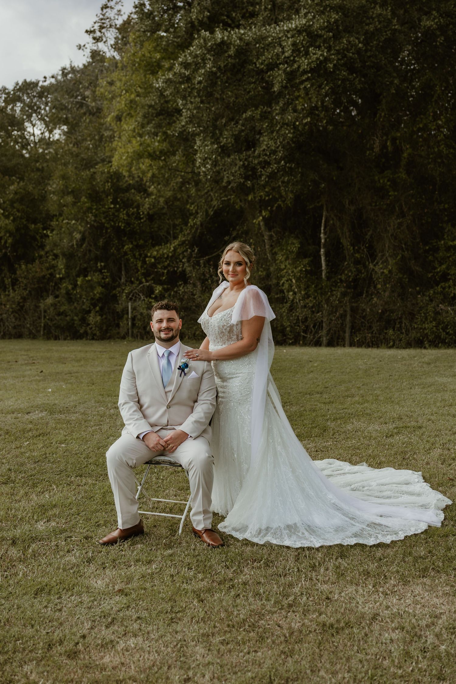 Wedding portraits of a couple sitting together on a grassy hillside at sunset.