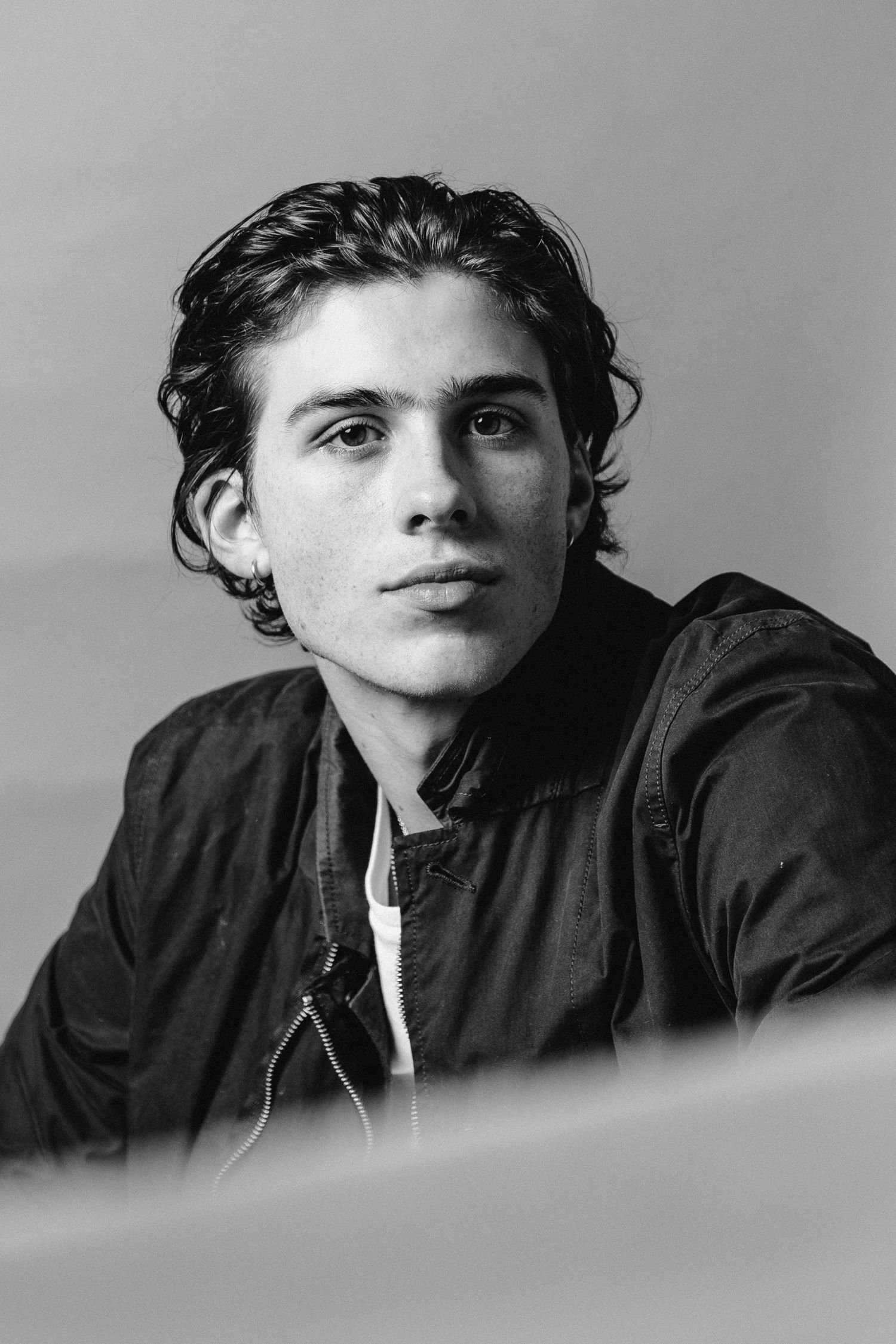 A black and white portrait photograph of a person wearing a dark jacket against a plain background.
