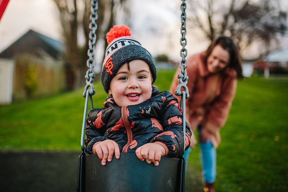 Series of playful outdoor photos showing a child swinging and laughing at a playground.