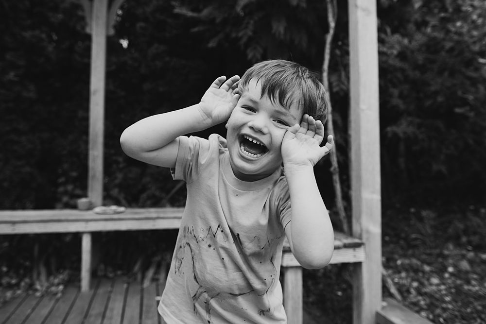 Child expressing pure joy and laughter while playing outdoors in natural lighting.