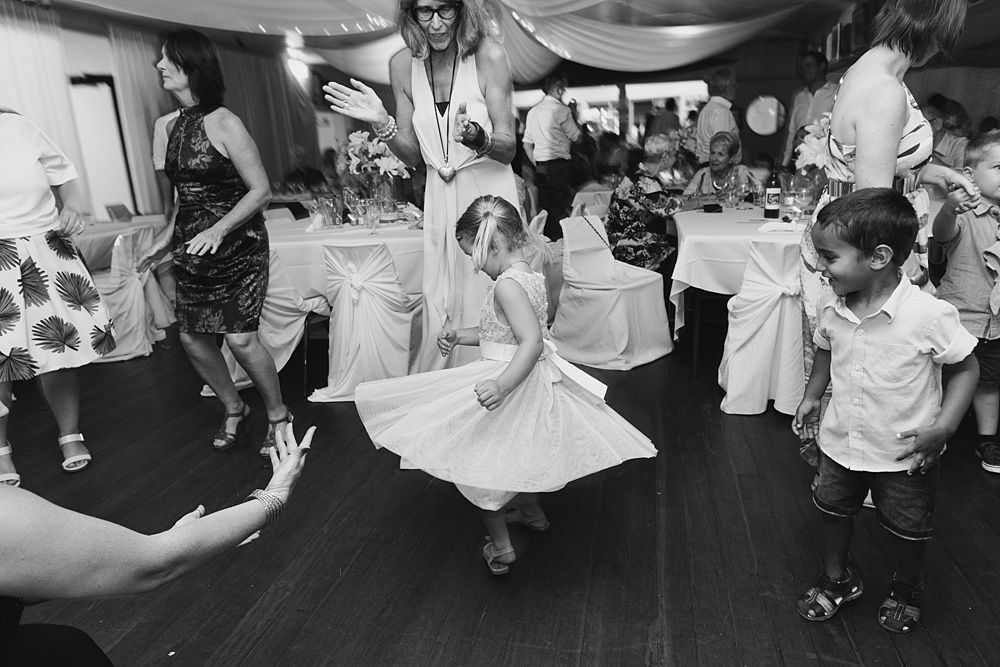 Black and white photo of wedding guests dancing on a reception dance floor.