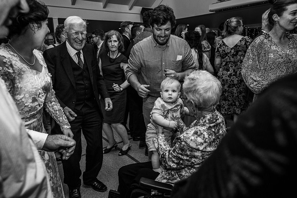 Wedding reception guests dancing and celebrating in black and white photography.