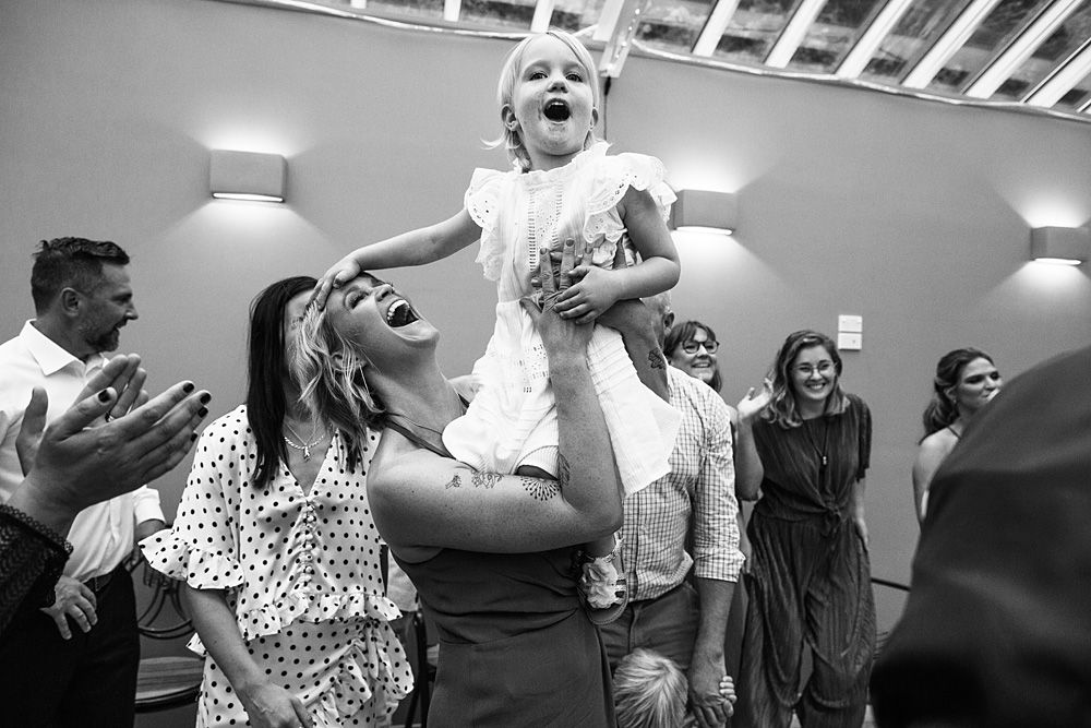Joyful people dancing and celebrating at an indoor event with bright lighting.