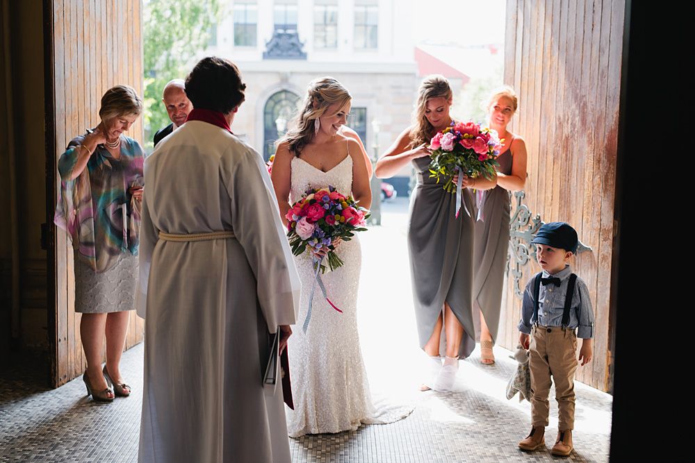 Wedding party walking through a tunnel-like passageway with natural light streaming in from outside.