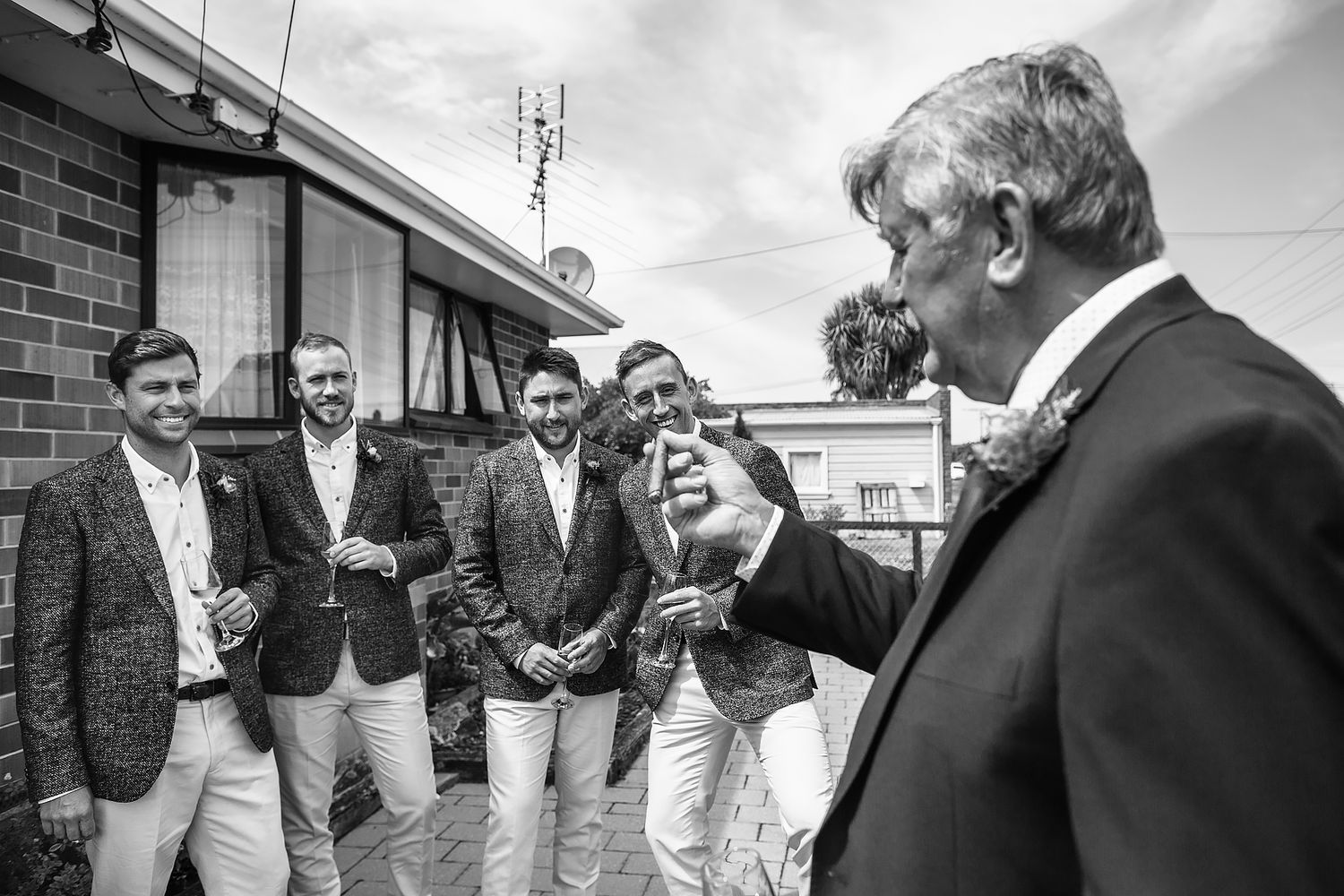Black and white photo of wedding party gathering outside brick building.