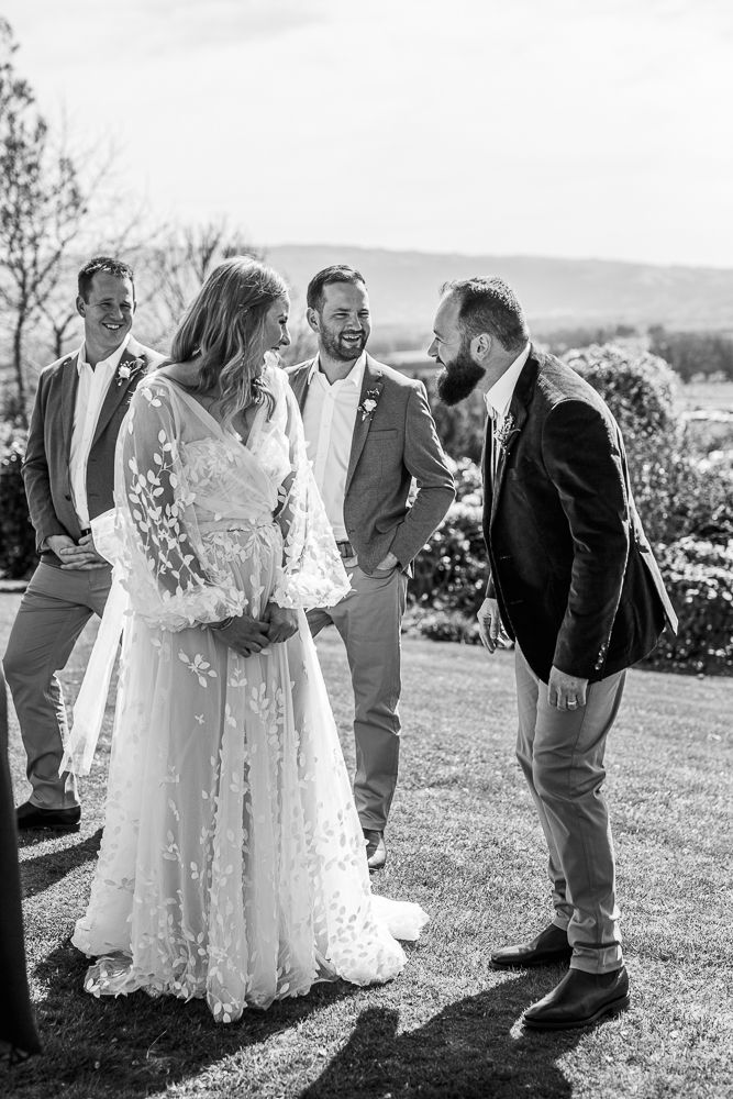 Black and white wedding photos showing joyful moments between a couple and guests in an outdoor garden setting.