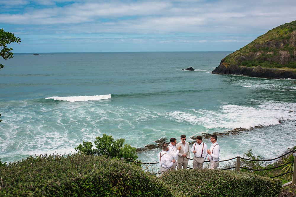 Panoramic coastal view of ocean waves crashing against cliffs under blue sky.