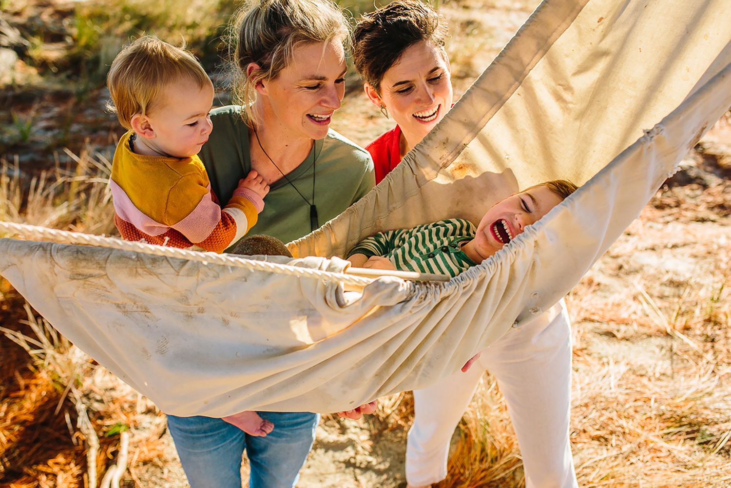 Family enjoying a fun outdoor picnic together on a sunny autumn day with blankets spread on fallen leaves.
