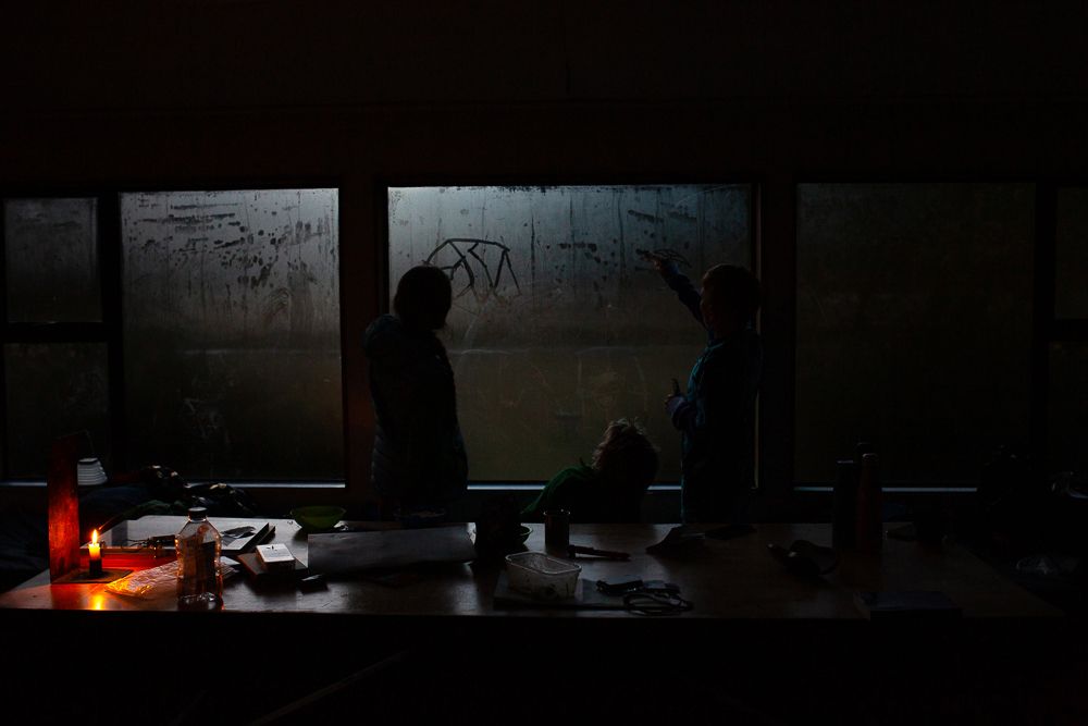 Silhouettes of people gathered around a dimly lit table with a red light glowing in the darkness.