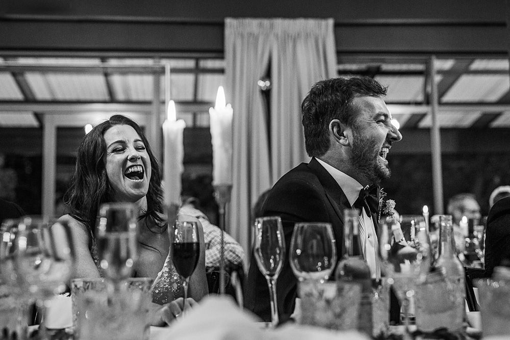 Black and white candid shots of guests laughing during wedding speeches.