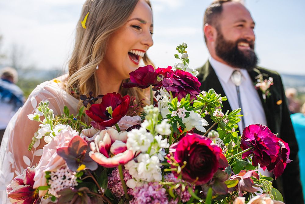 A couple shares a joyful moment with vibrant pink and white wedding bouquet flowers.