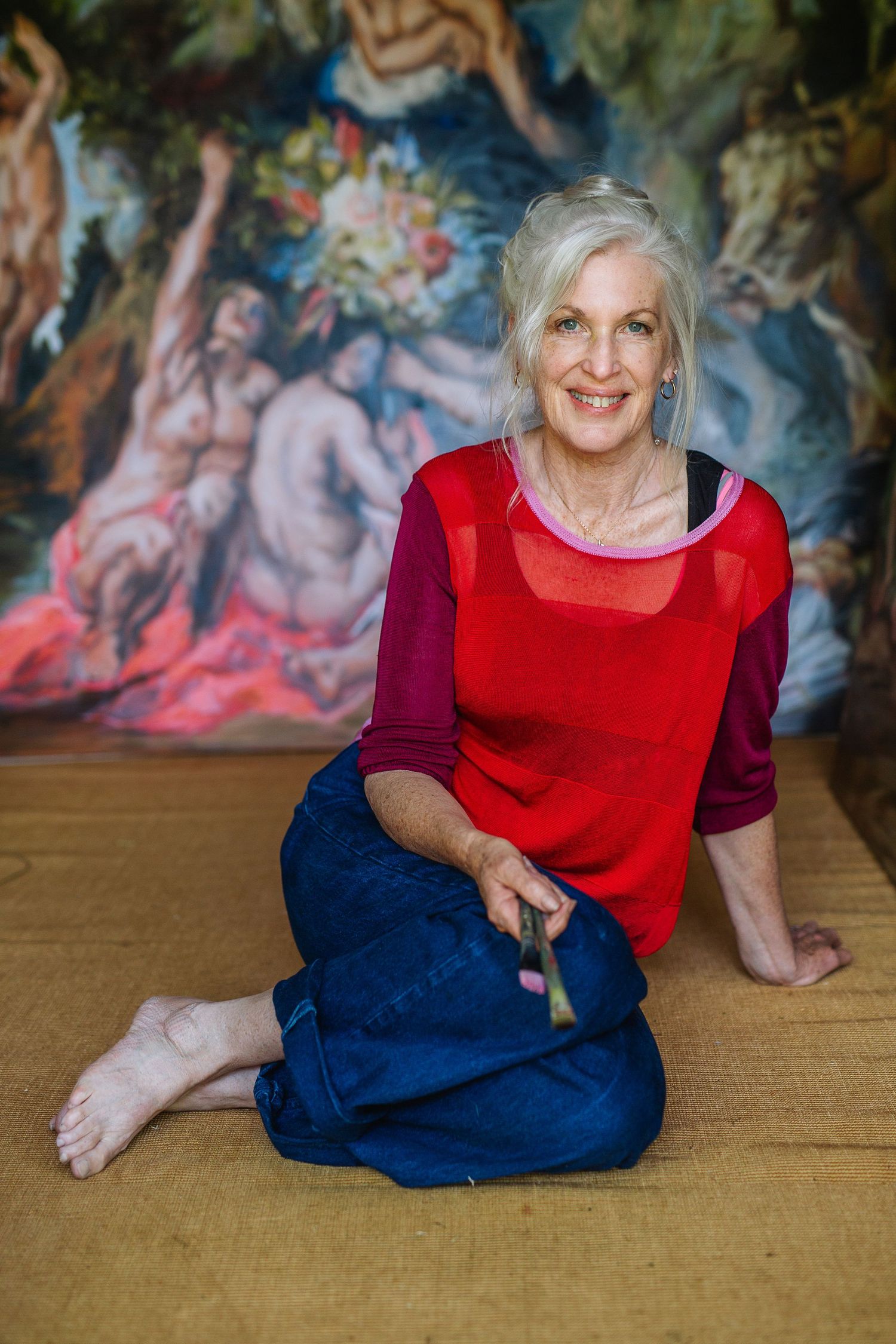Person sitting on wooden floor against vibrant artistic wall mural.