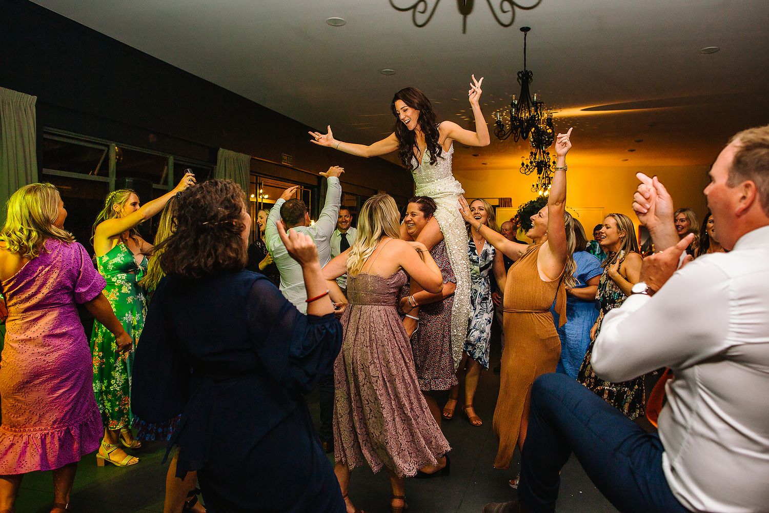 An energetic wedding reception dance party with guests celebrating on the dance floor.
