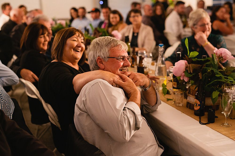Wedding reception guests enjoying dinner and conversation at long tables.
