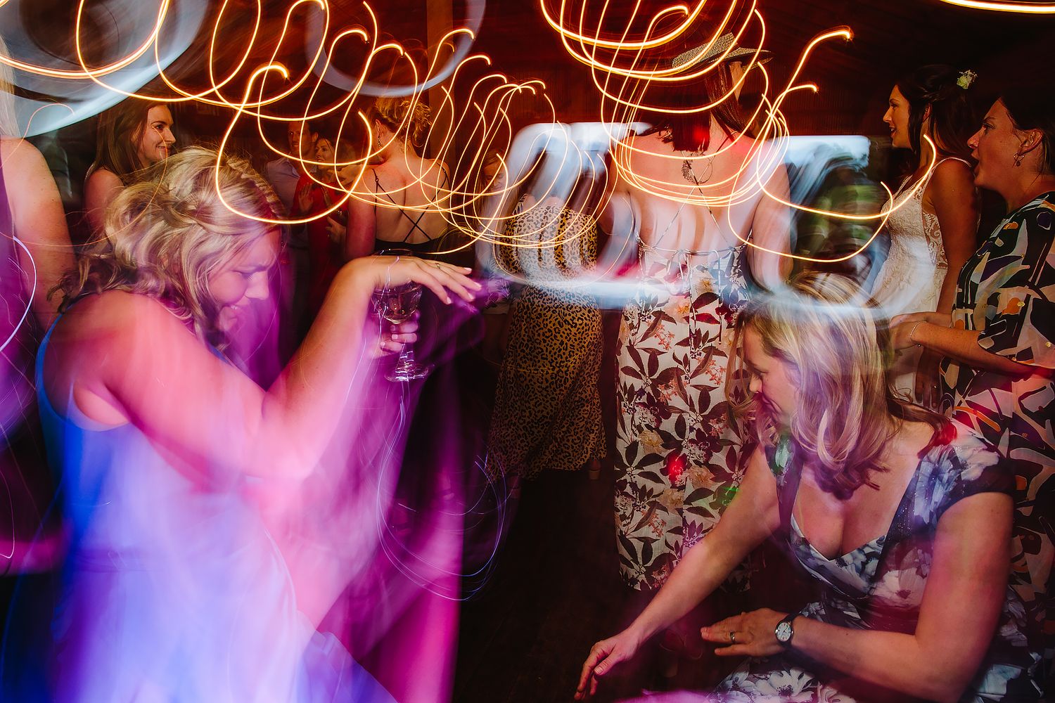 Colorful light trails and motion blur capture dancing at a lively party.