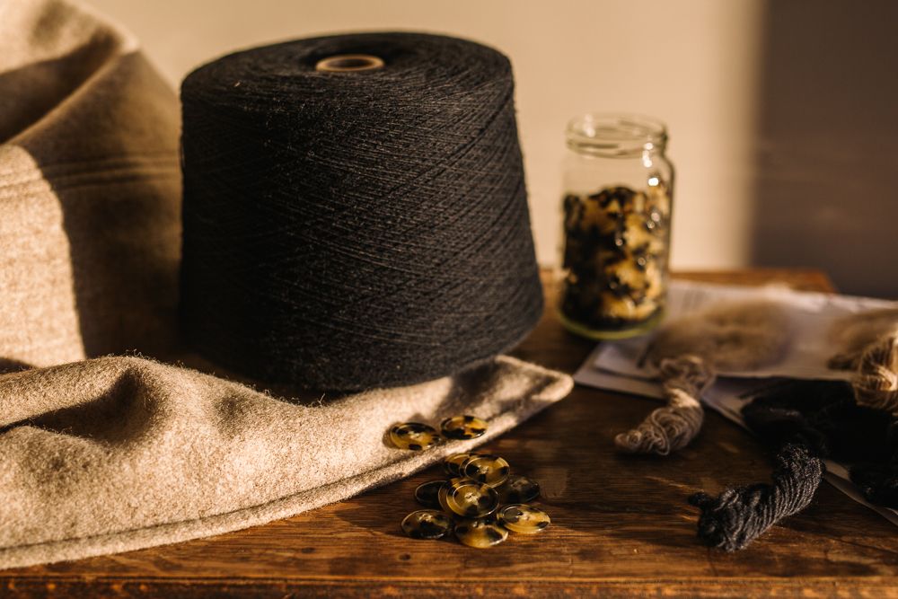 Large black thread spool with vintage fabric and dried flowers on wooden surface.