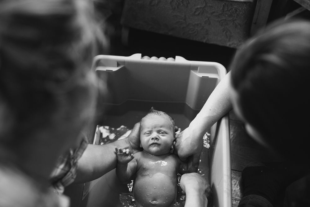 Close-up black and white image showing gentle hands holding a sleeping infant.