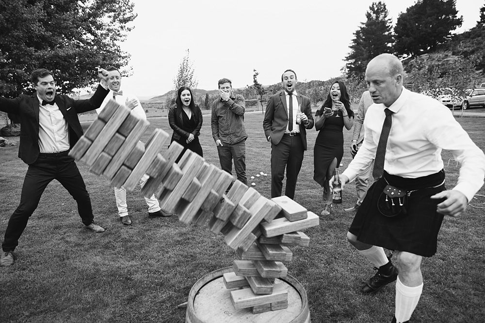 Wedding guests play outdoor party games on a grassy lawn during reception.