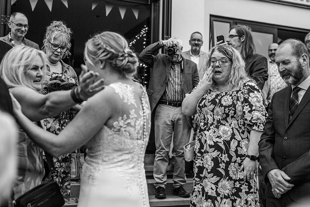 Black and white candid shot of wedding guests dancing and celebrating.