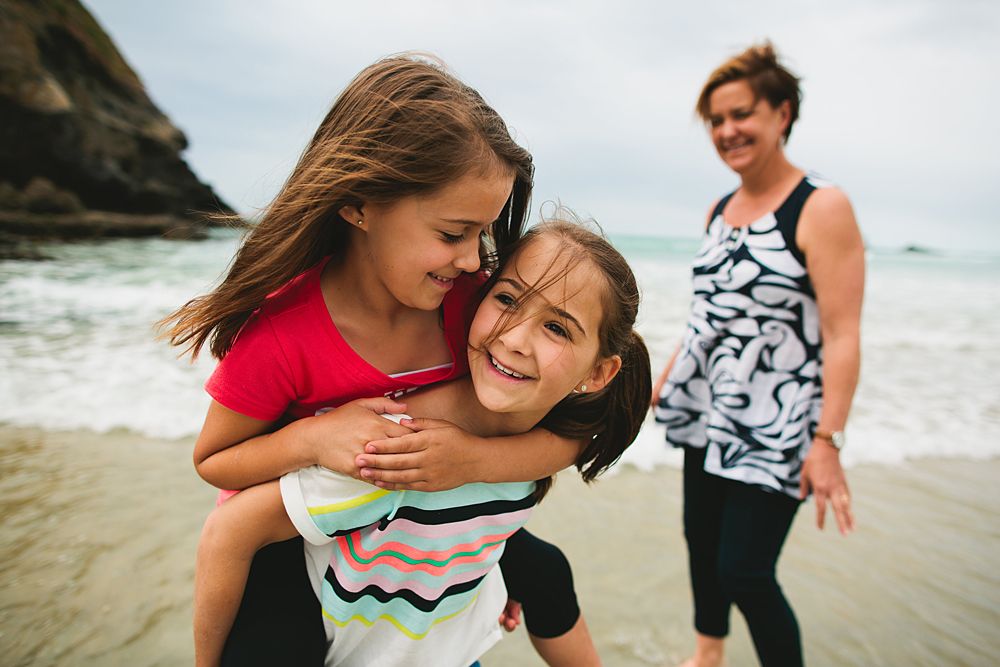 Joyful interactions captured on a sunny beach with waves in the background.