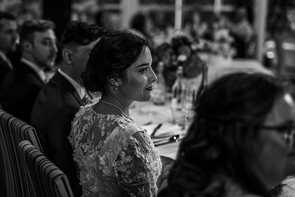 Black and white candid reception scene with guests at dining tables.