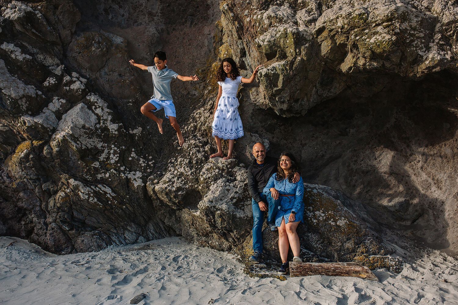 Playful group photos taken against dramatic rocky beach formations.