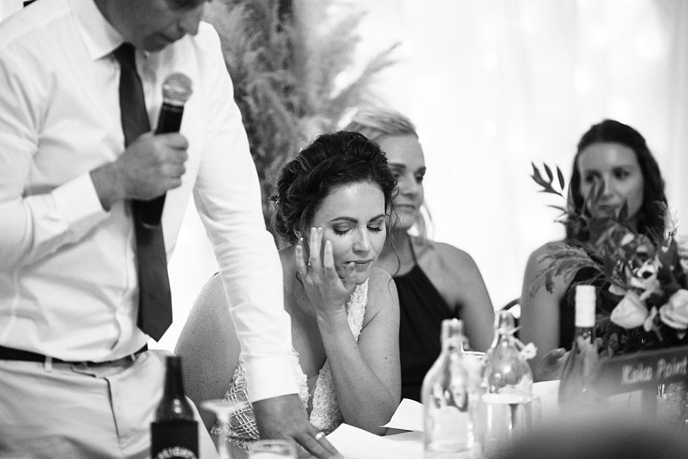 Black and white photo capturing laughter during wedding reception speeches.
