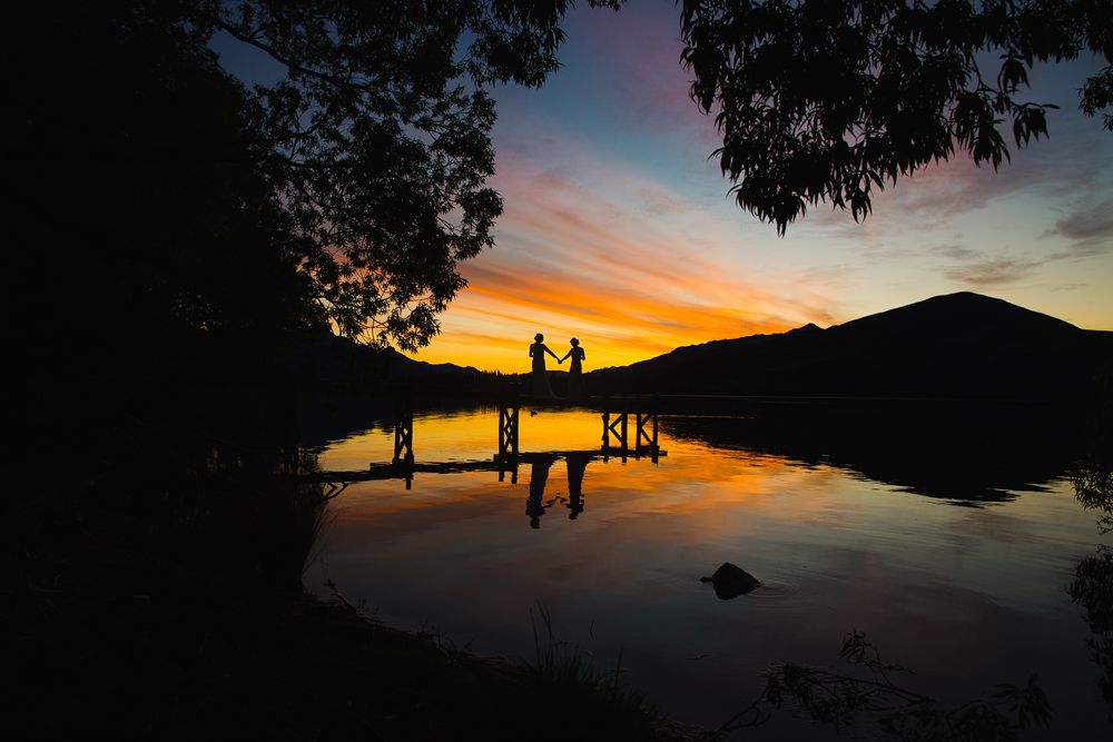 Stunning sunset silhouettes over a lake with trees framing the golden sky.