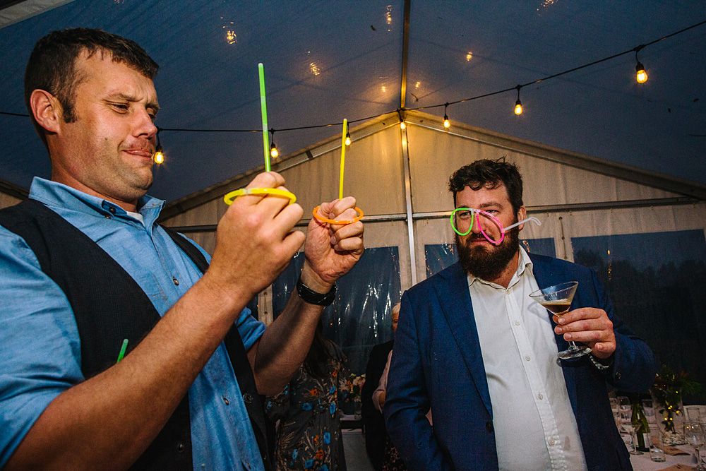 Evening celebration under string lights with guests enjoying drinks and conversation.