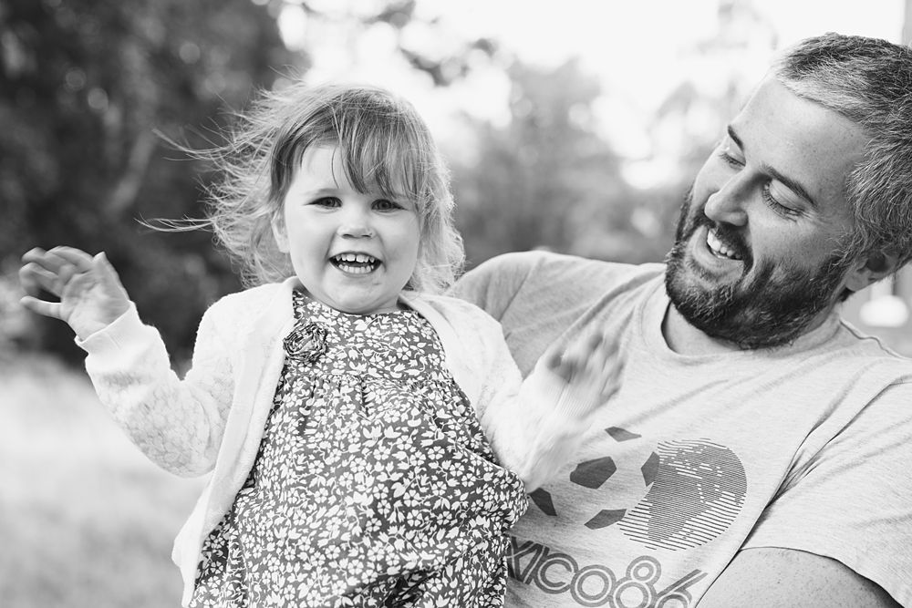 Black and white portrait captures tender family moment outdoors.