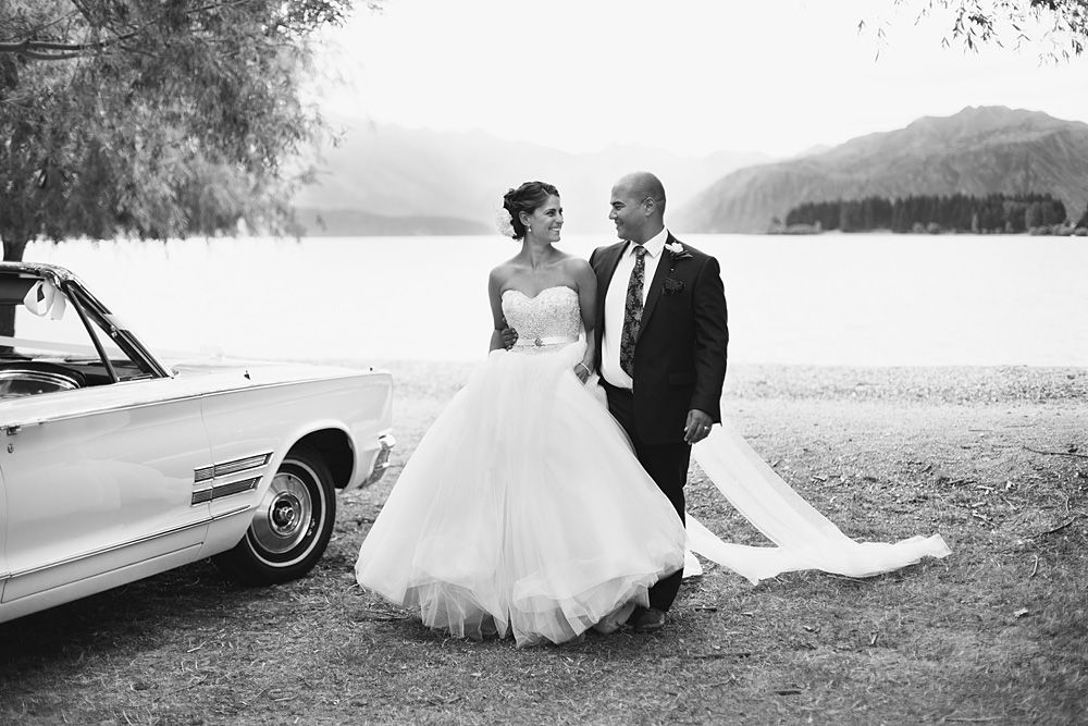 Classic wedding portraits taken near vintage cars with mountain scenery.