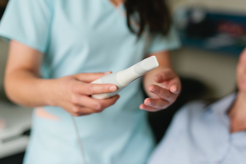 Healthcare worker holding medical device in clinical setting.