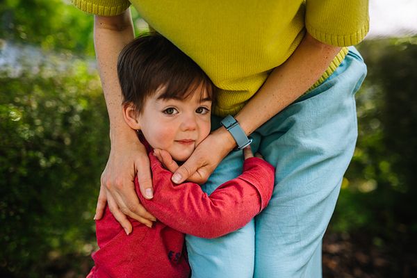 Parent and child sharing a tender moment outdoors in casual clothing.