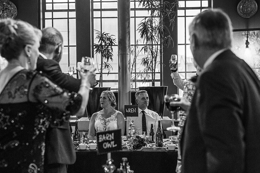 Wedding reception guests mingle in elegant indoor venue with large windows.