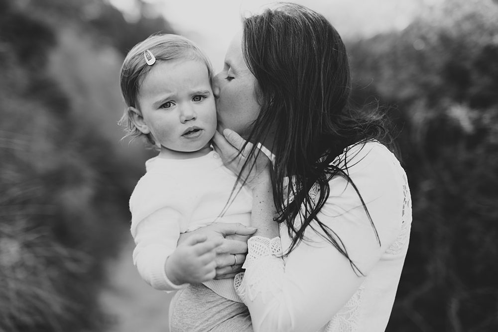 Black and white portrait of tender family moment in natural setting.