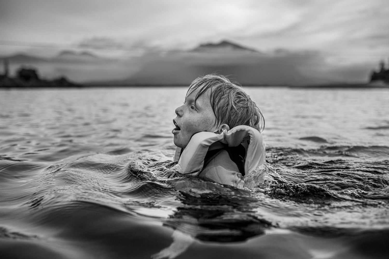 Dramatic black and white photo series of a swimmer moving through dark ocean waters at sunset.