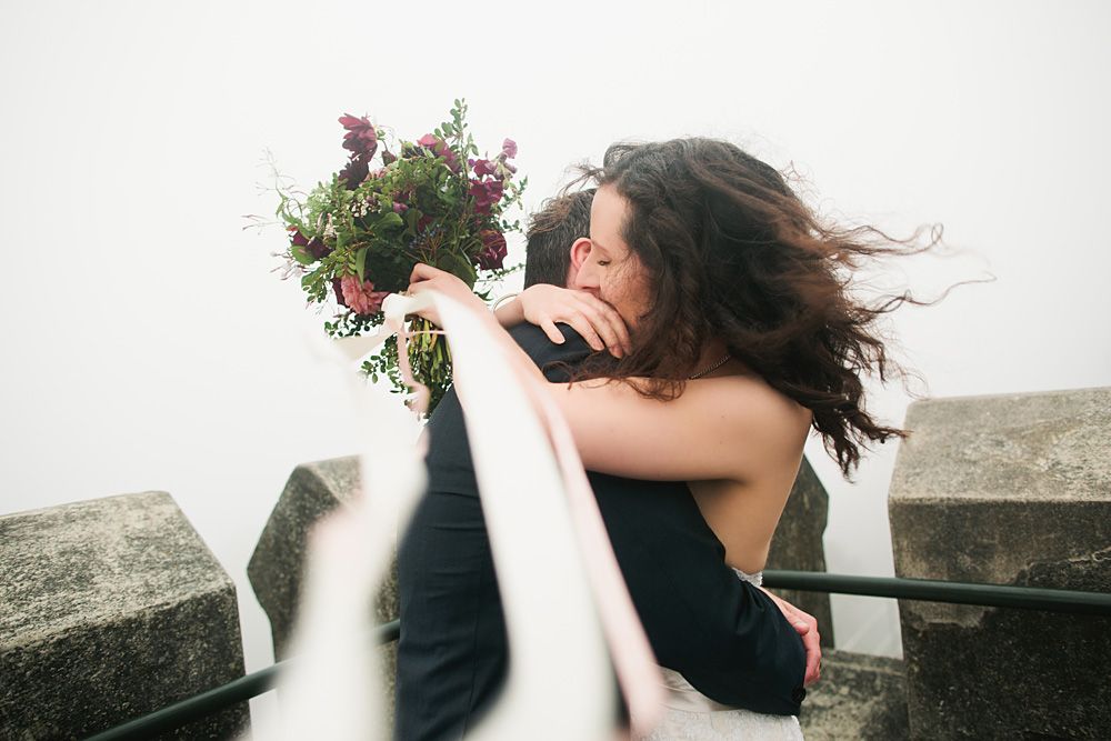 Couple embracing in an intimate moment against a bright white background.