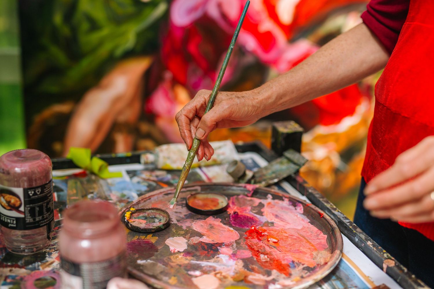 Hands working with art supplies and paint on a colorful surface.
