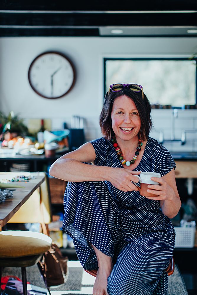 Woman in navy polka dot dress lounging casually in bright office space.