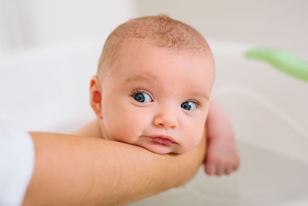 A close-up view of an infant's face with bright blue eyes looking to the side.