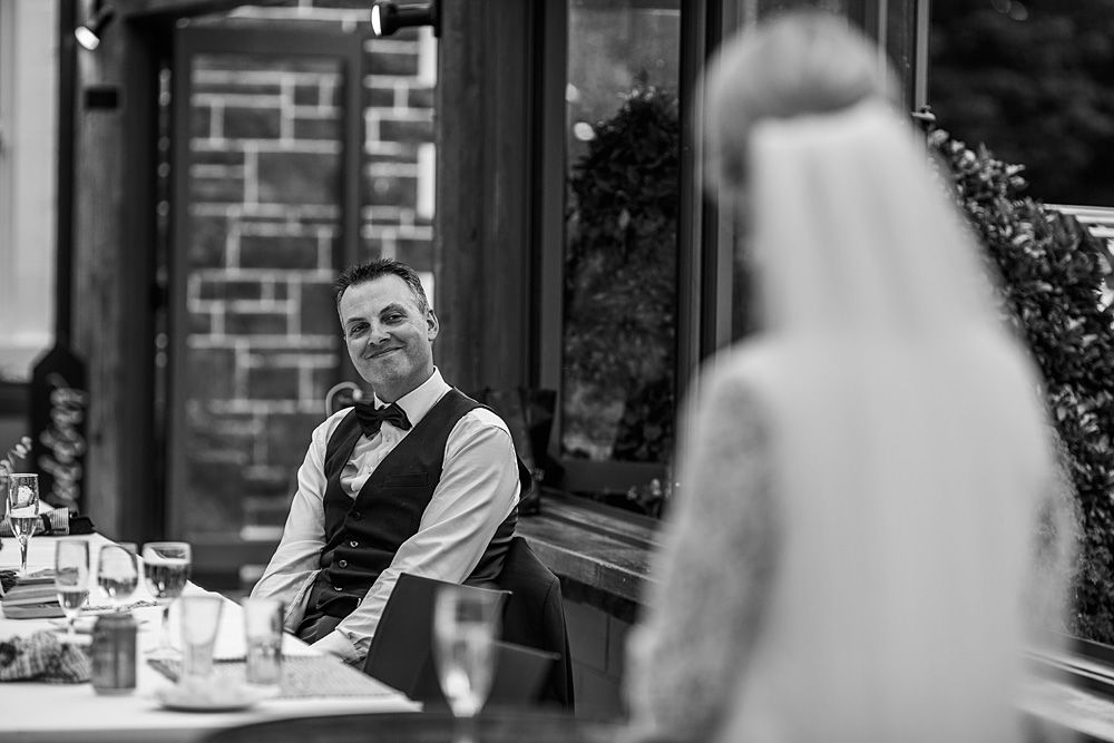 Wedding reception candid moments captured through window reflections.