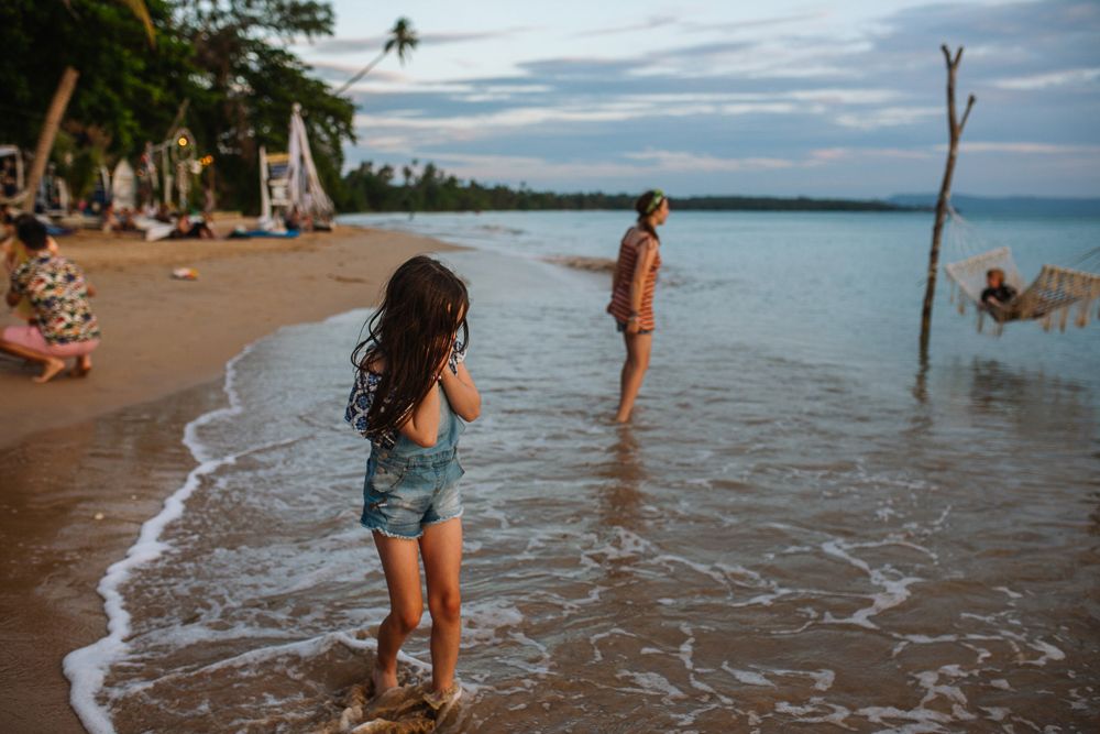 People enjoying a sunny day at a beach with gentle waves lapping the shore.