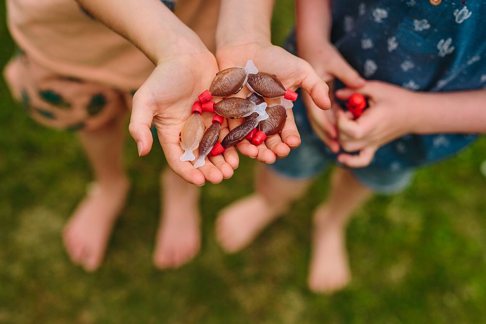 Close-up of hands holding small red objects during a group activity.