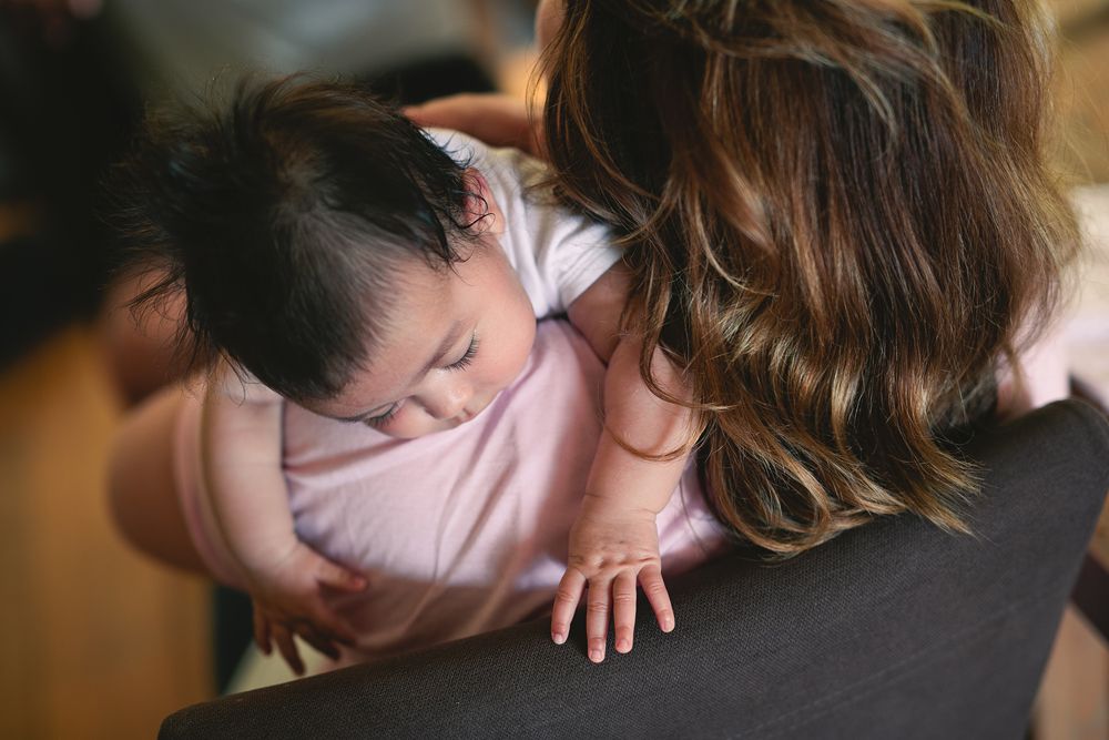 A tender black and white portrait of a baby being gently cradled and kissed.