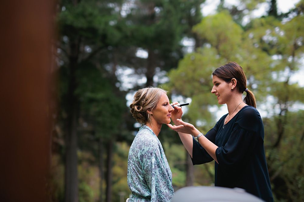 An outdoor makeup application session during wedding preparations.