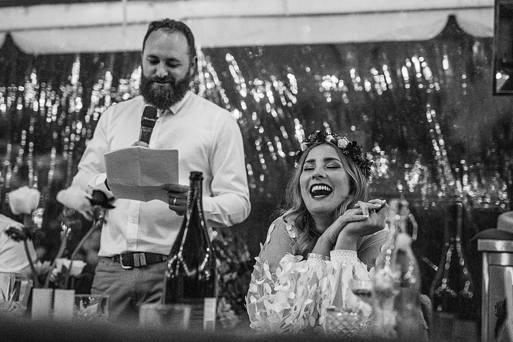 Black and white photo of wedding guests laughing and celebrating outdoors.